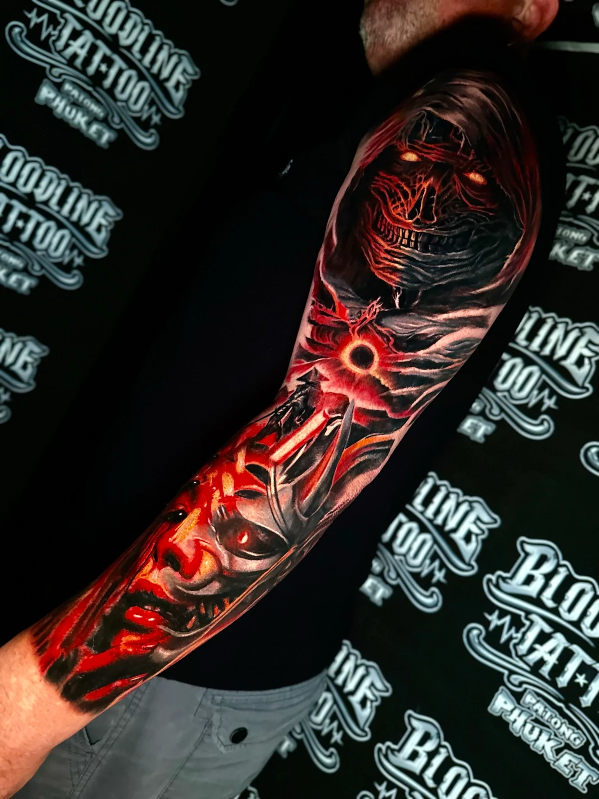 Dark fantasy colour sleeve with a hooded wraith, a glowing eclipse portal, and a layered Oni demon mask in red and orange at Bloodline Tattoo Phuket.