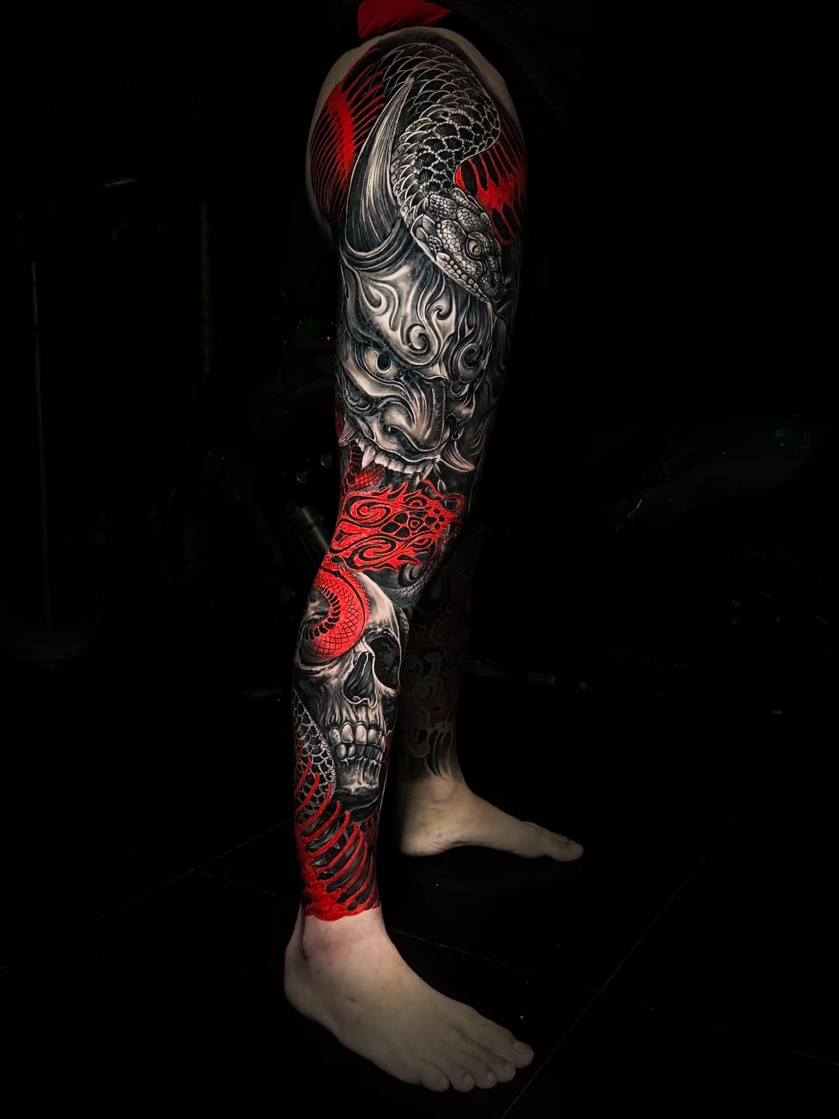 Japanese full leg sleeve with Hannya mask, coiled snake, skull on the shin, and vivid red accents at Bloodline Tattoo Phuket.