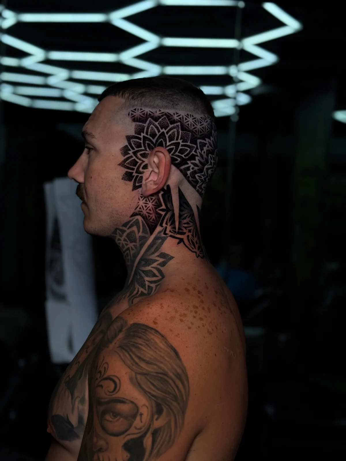 Side-of-head mandala work with a large lotus framing the ear, Flower of Life temple geometry, and dense neck blackwork dotwork panels, at Bloodline Tattoo Phuket.