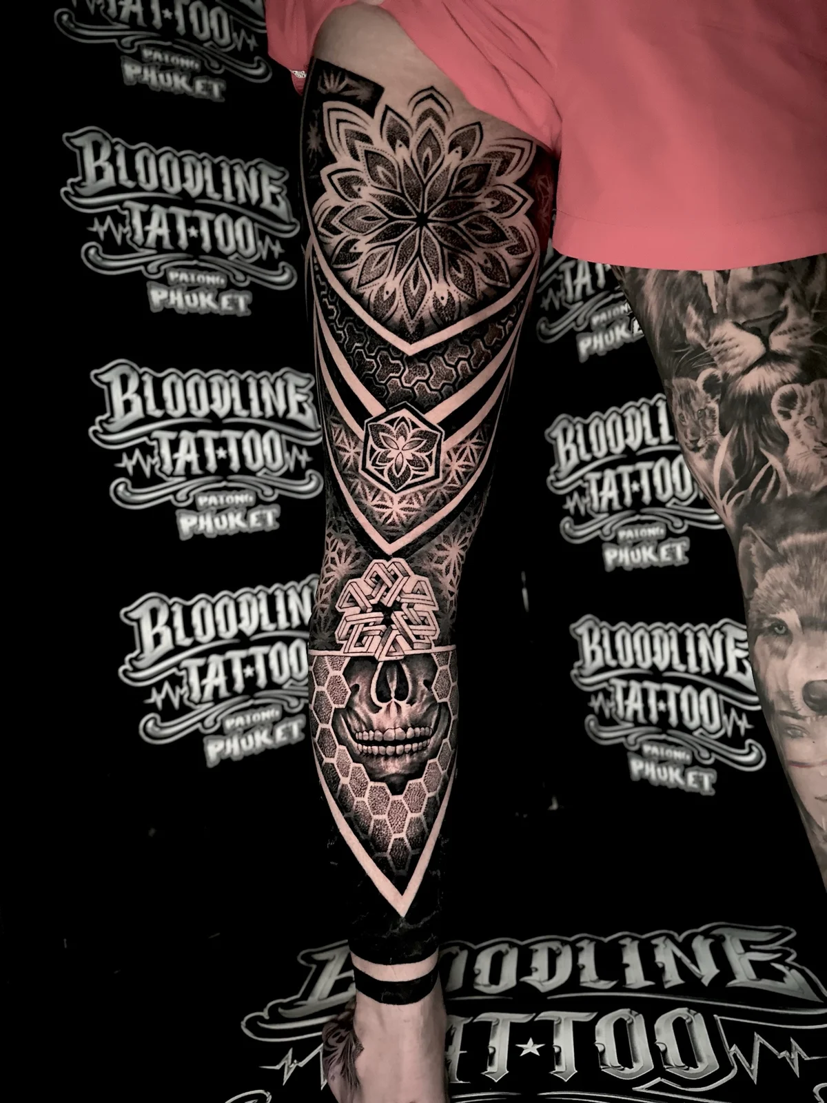 Front leg mandala tattoo with a thigh lotus mandala, a 3D geometric knee knot, and a skull set in a honeycomb shin grid at Bloodline Tattoo Phuket.