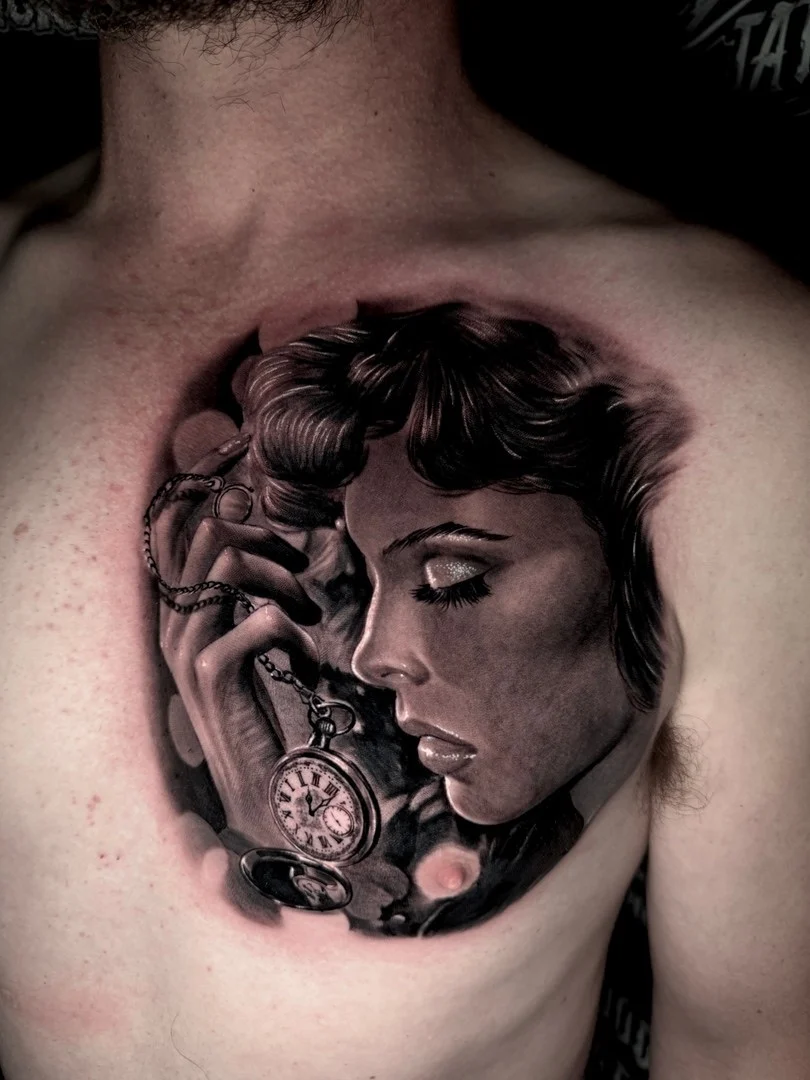 Black and grey portrait realism chest tattoo of a woman in profile holding an open pocket watch at Bloodline Tattoo Phuket.